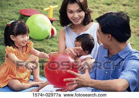 Stock Image - Parents sitting with their son and daughter on a lawn. Fotosearch