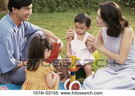 Parents sitting with their two daughters in a park View Large Photo Image Stock Photography - Parents sitting with their two daughters in a park. Fotosearch