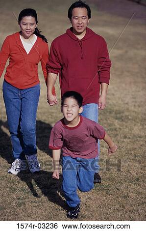 Stock Photograph - Parents walking on a lawn with their son. Fotosearch