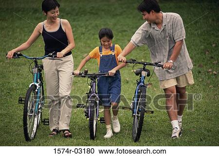 Parents with their daughter walking with bicycles in a park View Large Photo Image Stock Image - Parents with their daughter walking with bicycles in a park. Fotosearch