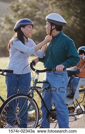 Stock Image - Parents with their son wearing cycling helmets. Fotosearch
