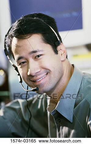Stock Photography - Portrait of a businessman wearing a headset smiling. Fotosearch