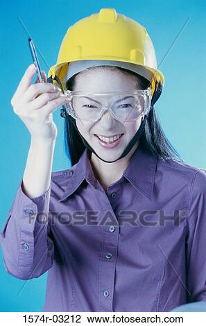 Stock Image - Portrait of a construction worker wearing a hardhat holding a pen. Fotosearch