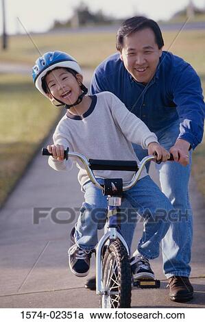 Portrait of a father helping his son ride a bicycle View Large Photo Image Stock Image - Portrait of a father helping his son ride a bicycle. Fotosearch