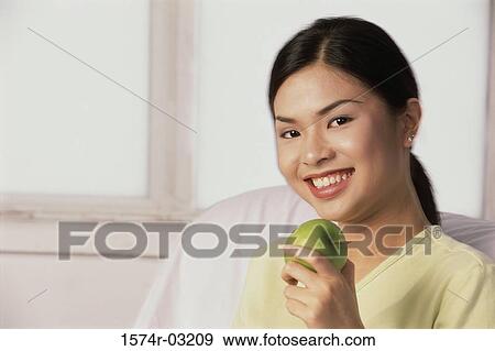 Portrait of a young woman holding an apple View Large Photo Image Stock Photo - Portrait of a young woman holding an apple. Fotosearch