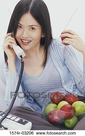 Stock Photograph - Portrait of a young woman talking on a telephone. Fotosearch