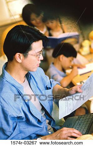 Side profile of a father working on a laptop with his family sitting behind him View Large Photo Image Stock Photo - Side profile of a father working on a laptop with his family sitting behind him. Fotosearch