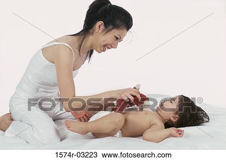 Stock Image - Side profile of a mother playing with her baby boy. Fotosearch