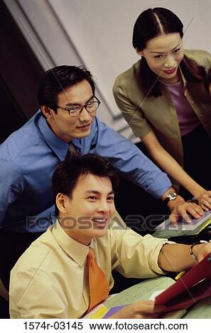 Stock Photography - Two businessmen and a businesswoman in an office. Fotosearch