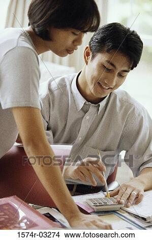 Young couple calculating bills using a calculator View Large Photo Image Picture - Young couple calculating bills using a calculator. Fotosearch