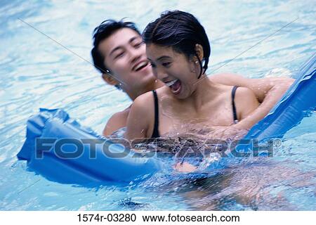 Young couple enjoying in a swimming pool View Large Photo Image Stock Image - Young couple enjoying in a swimming pool. Fotosearch