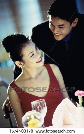 Young couple smiling at each other at a dining table View Large Photo Image Stock Photo - Young couple smiling at each other at a dining table. Fotosearch