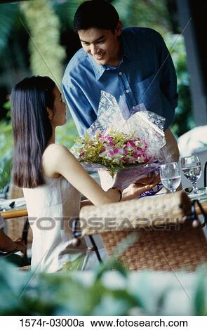 Young man giving a bouquet of flowers to a young woman View Large Photo Image Stock Image - Young man giving a bouquet of flowers to a young woman. Fotosearch