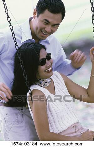 Picture - Young man pushing a young woman on a swing. Fotosearch
