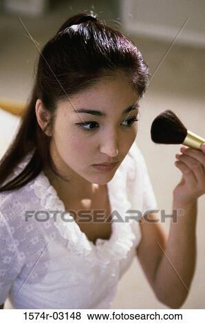 Young woman applying make-up with a brush View Large Photo Image Stock Photo - Young woman applying make-up with a brush. Fotosearch