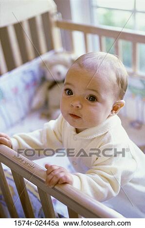 Stock Image - Baby boy standing in a crib. Fotosearch