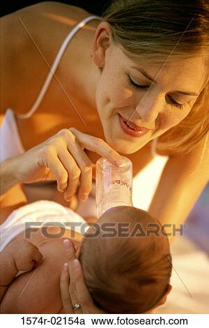 Close-up of a mother feeding her baby girl with a baby bottle View Large Photo Image Stock Image - Close-up of a mother feeding her baby girl with a baby bottle. Fotosearch