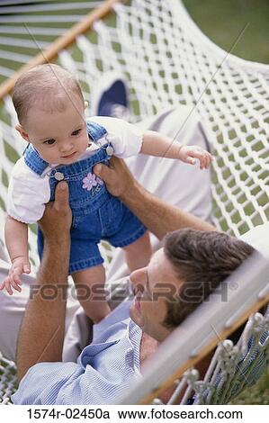 Father lying in a hammock holding up his baby boy View Large Photo Image Stock Image - Father lying in a hammock holding up his baby boy. Fotosearch