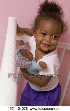 High angle view of a baby girl holding a doll View Large Photo Image Stock Photograph - High angle view of a baby girl holding a doll. Fotosearch