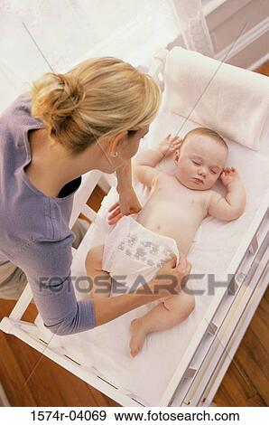 Mother putting a diaper on her baby boy View Large Photo Image Stock Photo - Mother putting a diaper on her baby boy. Fotosearch
