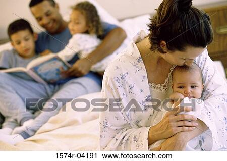 Stock Image - Parents and their children sitting on a bed. Fotosearch