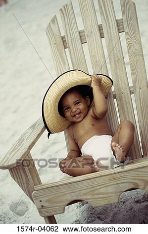 Portrait of a baby boy sitting on a wooden chair wearing a straw hat View Large Photo Image Stock Image - Portrait of a baby boy sitting on a wooden chair wearing a straw hat. Fotosearch