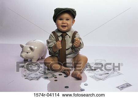 Picture - Portrait of a baby boy sitting on the floor with a piggy bank and money. Fotosearch