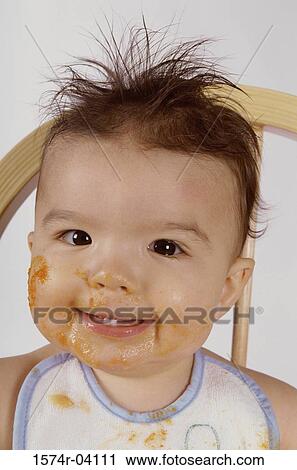Stock Image - Portrait of a baby boy smiling with food on his face. Fotosearch