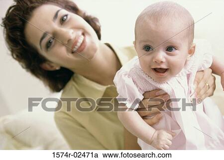 Stock Image - Portrait of a mother holding her baby girl. Fotosearch