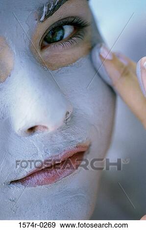 Stock Photo - Close-up of a young woman applying a facial mask with her finger. Fotosearch