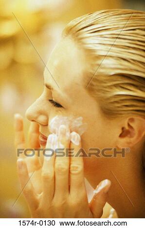 Close-up of a young woman applying moisturizer on her face View Large Photo Image Stock Image - Close-up of a young woman applying moisturizer on her face. Fotosearch