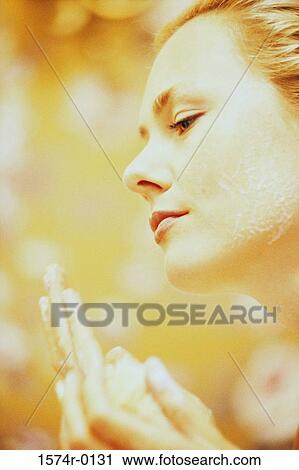 Stock Image - Close-up of a young woman applying moisturizer on her hands. Fotosearch