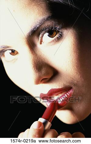 Close-up of a young woman applying lipstick View Large Photo Image Stock Image - Close-up of a young woman applying lipstick. Fotosearch