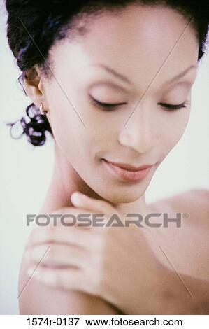 Stock Photo - Close-up of a young woman applying moisturizer on her shoulder. Fotosearch