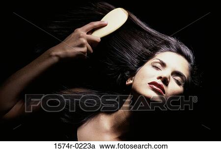 Close-up of a young woman brushing her hair View Large Photo Image Stock Image - Close-up of a young woman brushing her hair. Fotosearch
