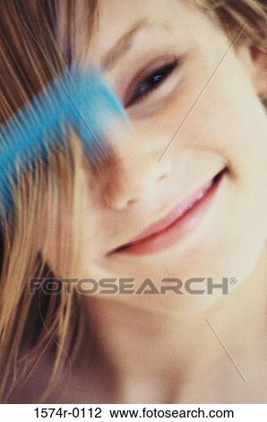 Close-up of a young woman combing her hair View Large Photo Image Stock Image - Close-up of a young woman combing her hair. Fotosearch