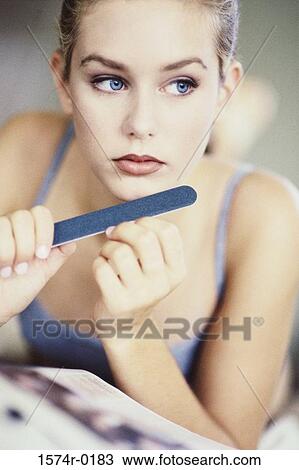 Close-up of a young woman filing her nails View Large Photo Image Stock Image - Close-up of a young woman filing her nails. Fotosearch
