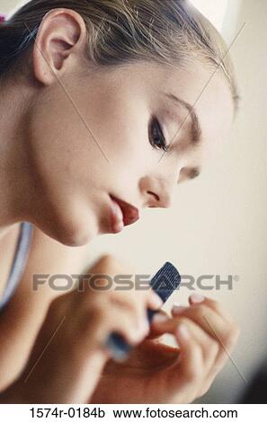 Stock Image - Close-up of a young woman filing her nails. Fotosearch