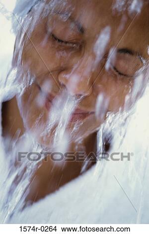 Picture - Close-up of a young woman splashing water on her face. Fotosearch