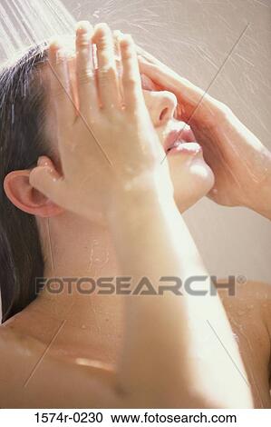 Stock Image - Close-up of a young woman taking a shower. Fotosearch