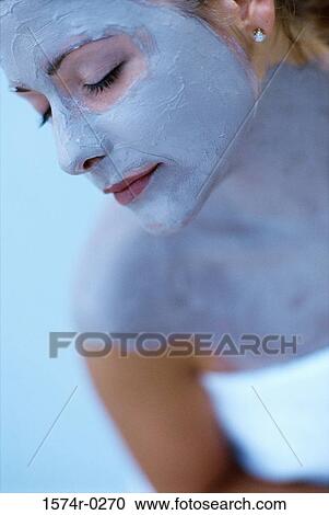 Stock Image - Close-up of a young woman wearing a facial mask. Fotosearch