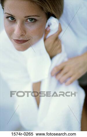 Stock Photography - Close-up of a young woman wiping her face with a towel. Fotosearch