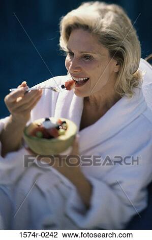 Mid adult woman eating fruit salad View Large Photo Image Stock Image - Mid adult woman eating fruit salad. Fotosearch