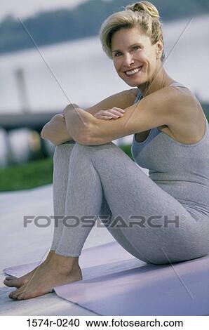 Stock Image - Portrait of a woman sitting on the floor smiling. Fotosearch