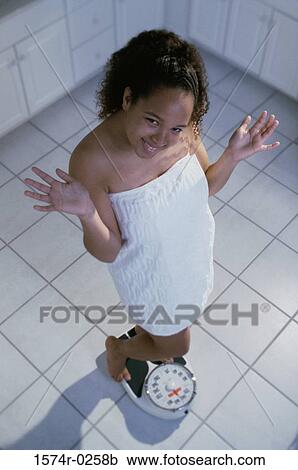 Stock Image - Portrait of a woman standing on a scale. Fotosearch