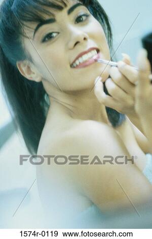 Stock Photo - Portrait of a young woman applying lipstick. Fotosearch