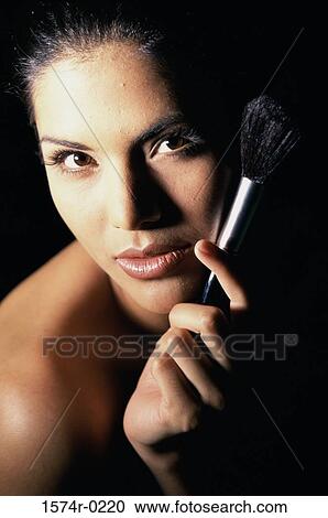 Portrait of a young woman holding a make-up brush View Large Photo Image Stock Image - Portrait of a young woman holding a make-up brush. Fotosearch