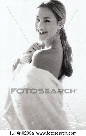 Stock Image - Portrait of a young woman wrapped in a towel at the beach. Fotosearch