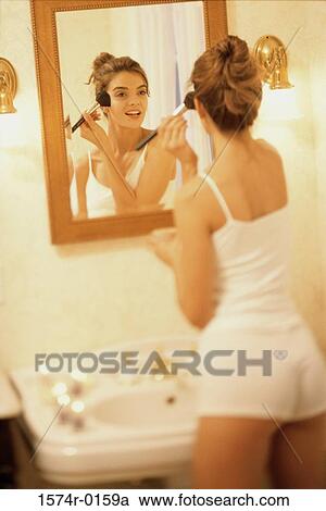 Rear view of young woman in a bathroom applying blush View Large Photo Image Stock Image - Rear view of young woman in a bathroom applying blush. Fotosearch