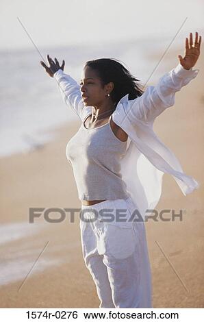 Stock Photograph - Side profile of a young woman stretching at the beach. Fotosearch